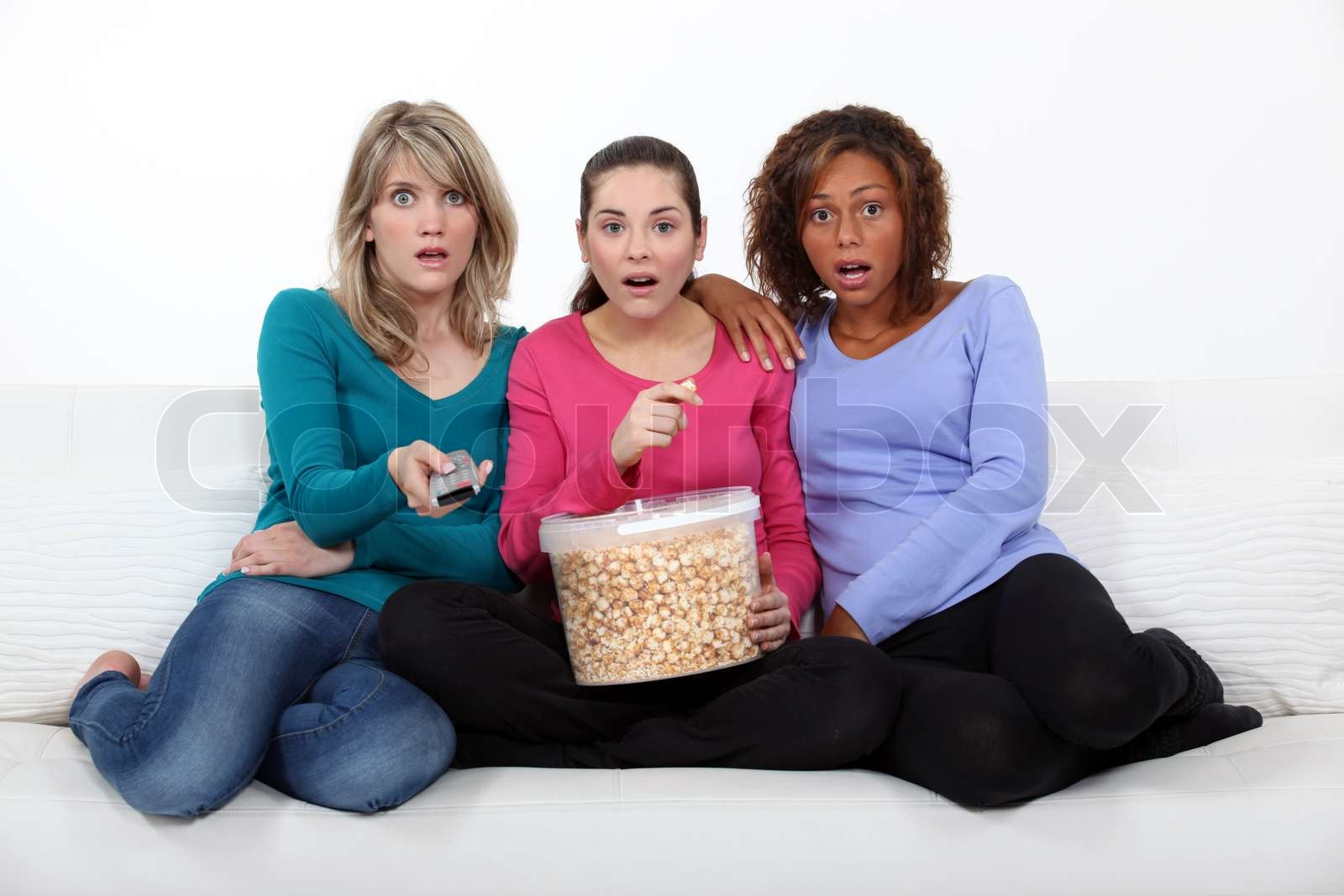 Drei verängstigte Frauen saßen auf dem Sofa bei einem Film | Stock Bild