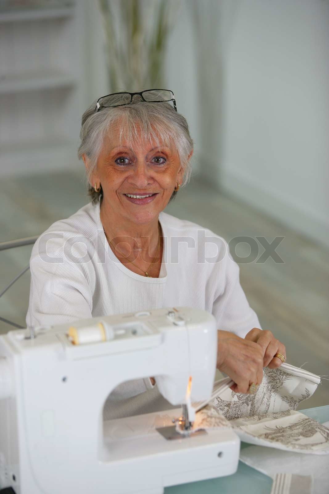 Elderly lady using sewing machine Stock image Colourbox