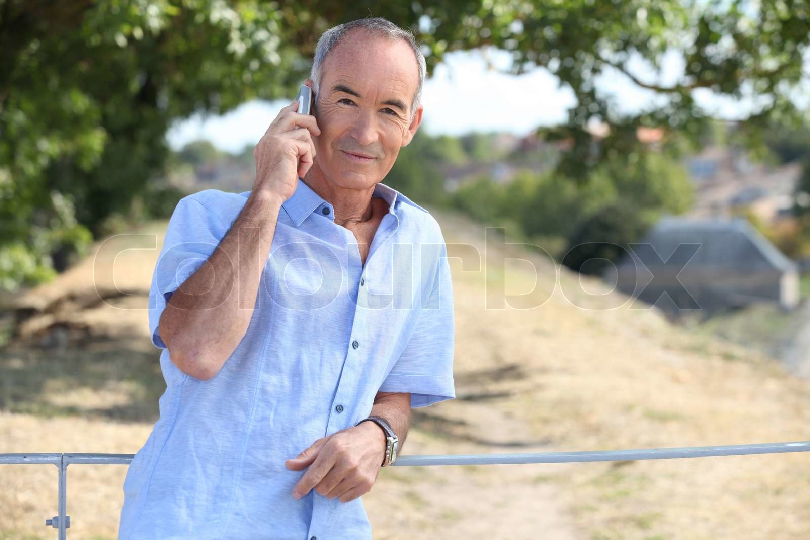 Mann mittleren Alters mit Mobiltelefon im Zoo Stock Bild Colourbox