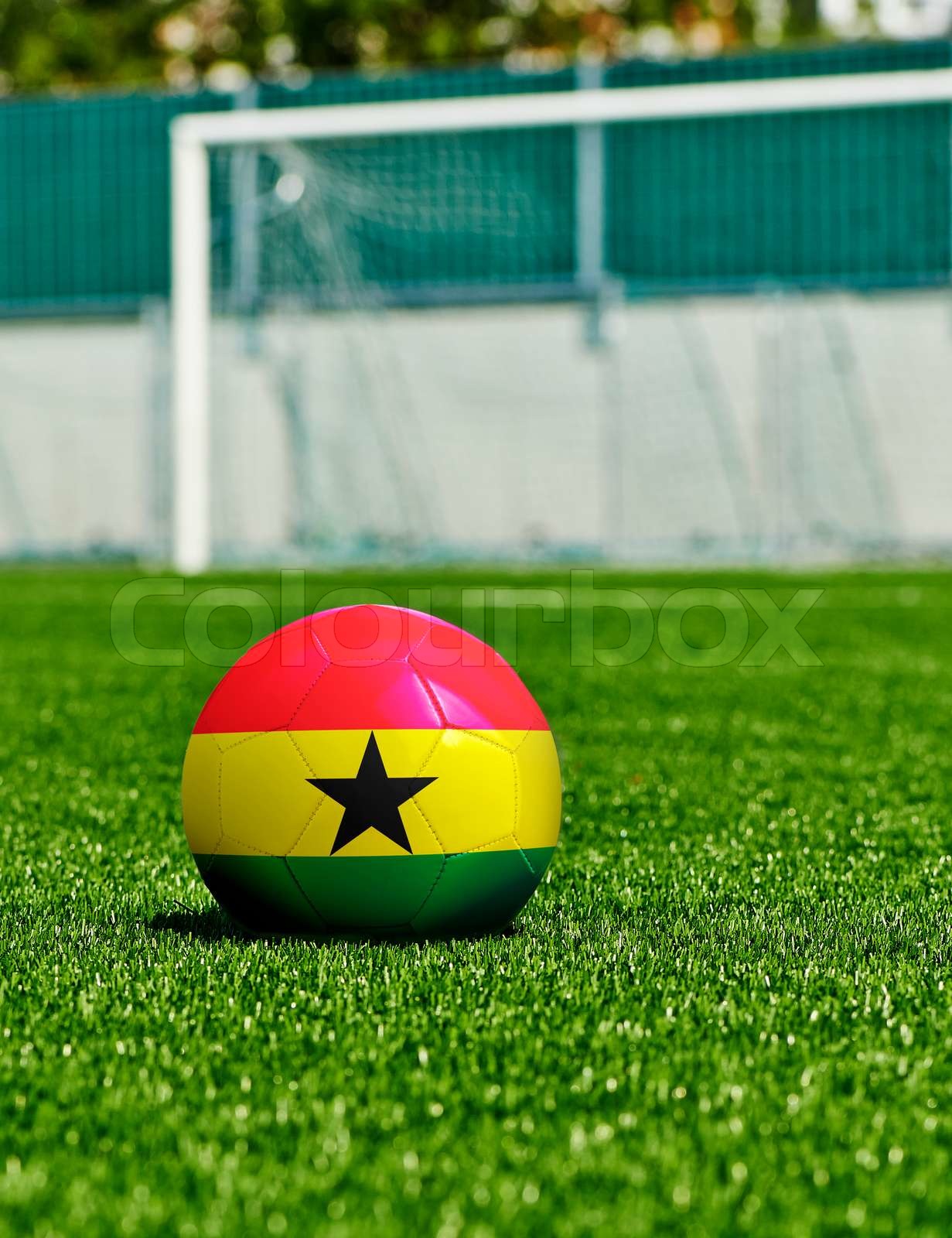 Soccer Ball with Ghana Flag on the grass in stadium Stock image