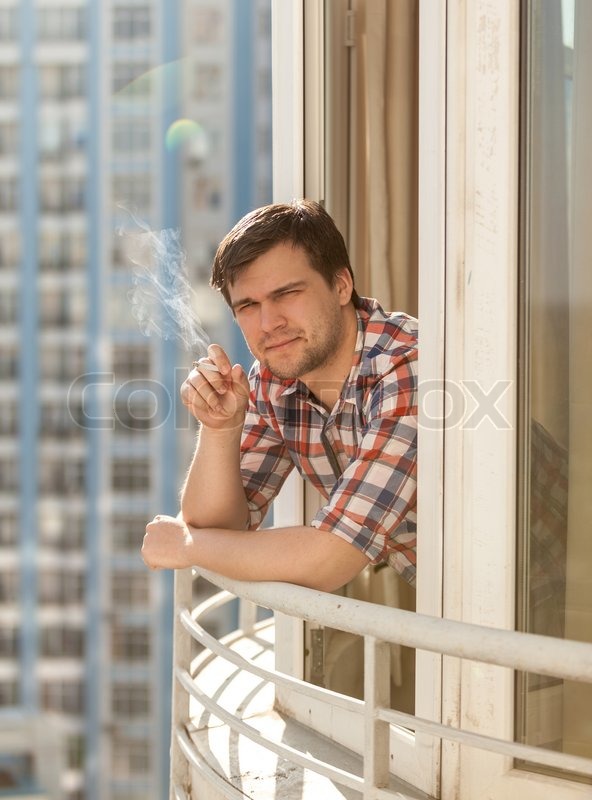 Portrait Of Sad Young Man Smoking Cigarette While Suffering From