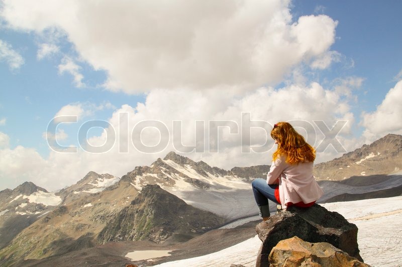 Young Girl Sitting On The Edge Of A Cliff And Looking At Sky With Clouds Mountain Peaks Young Girl Sitting On The Edge Of A Cliff And Looking At Sky With Clouds Mountain Peaks