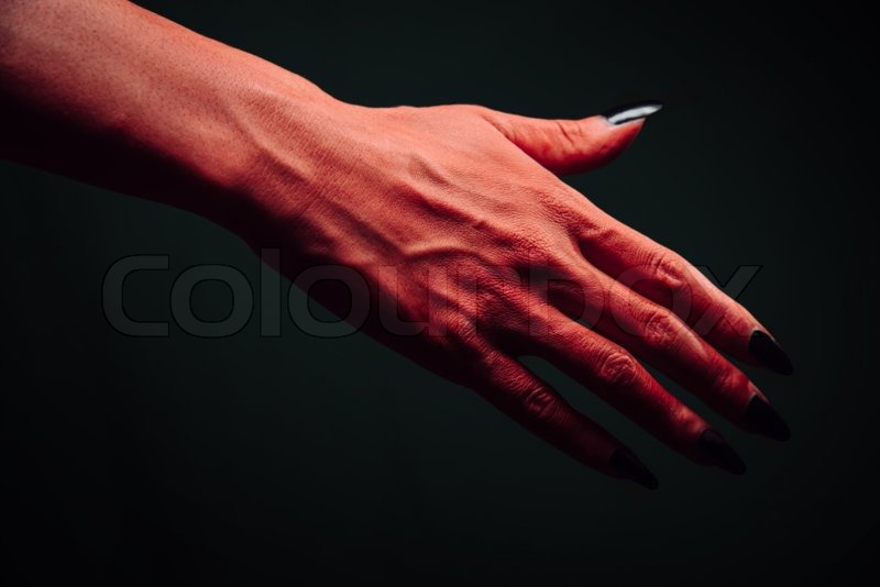 red demon or devil hand with handshake gesture on dark background