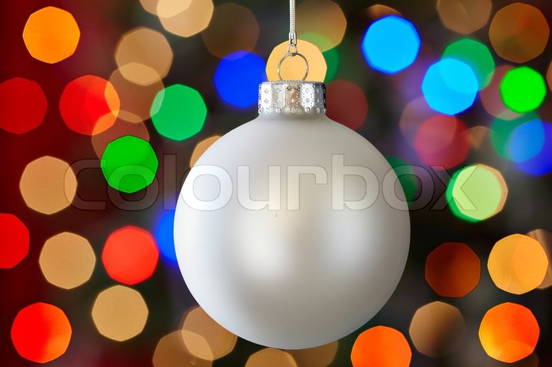 white christmas ornament over colorful multicolored christmas light