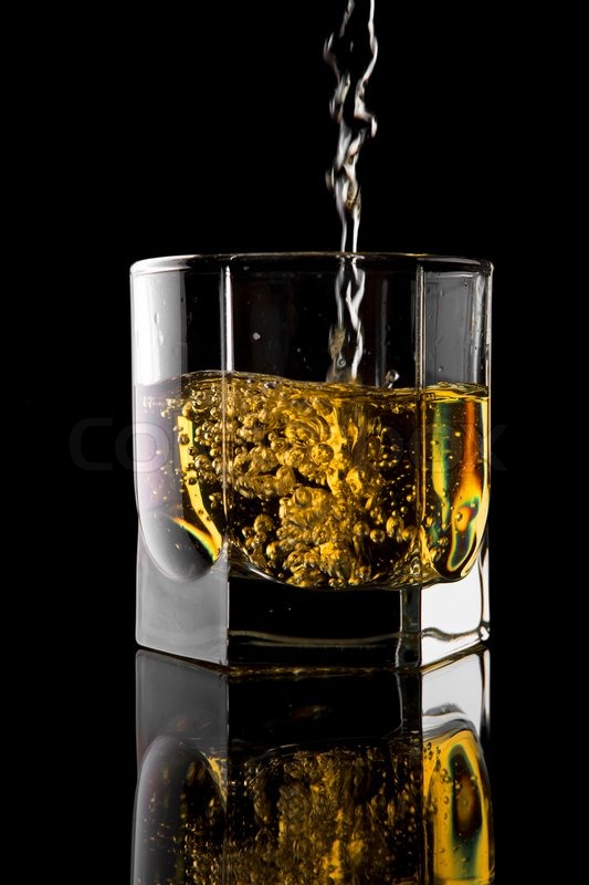 "Whiskey being poured into a glass against a black background" | Stock