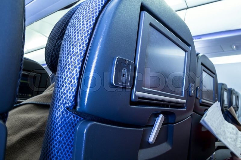 Back of modern airplane seats with small table and TV or electronic ... Back of modern airplane seats with small table and TV or electronic ...