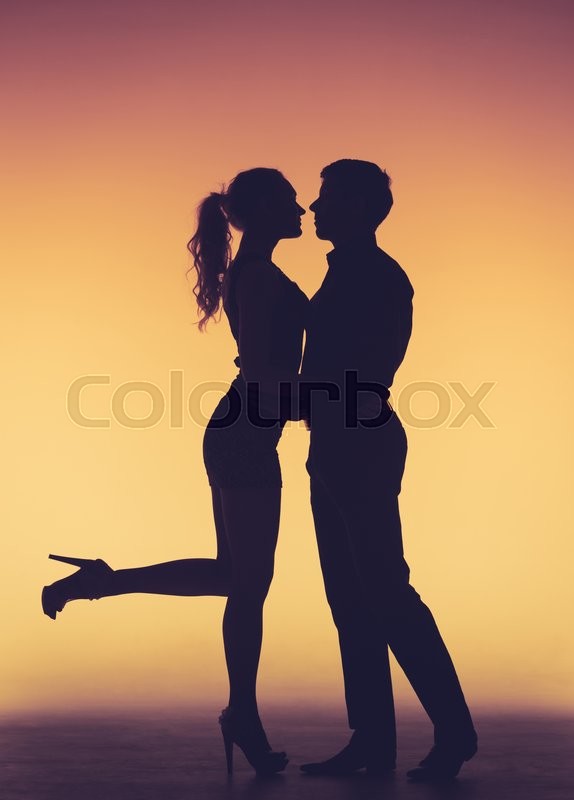 romantic couple kissing silhouettes on orange background stock