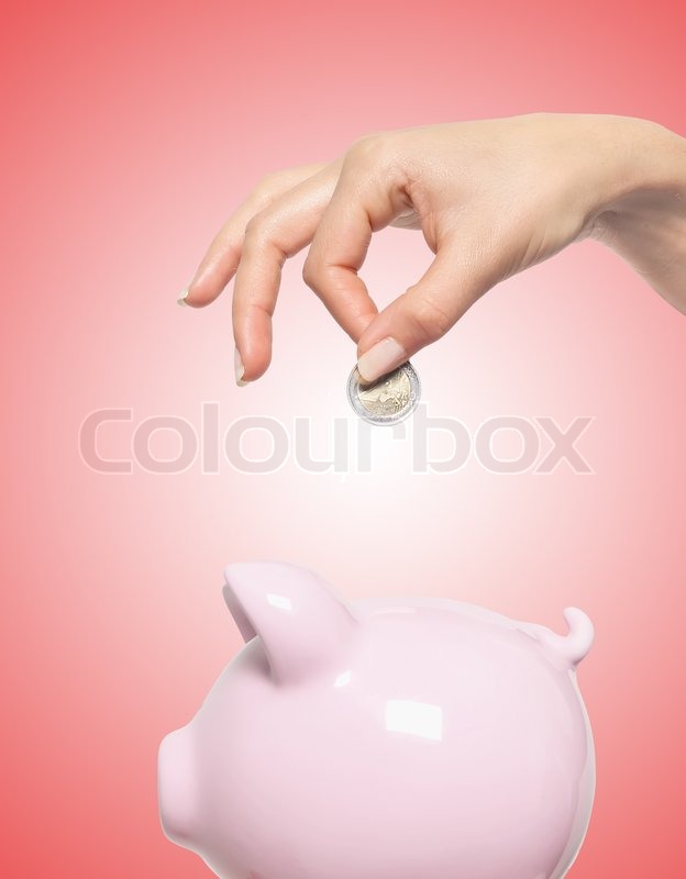 Hand putting money into the piggy bank ... | Stock image | Colourbox