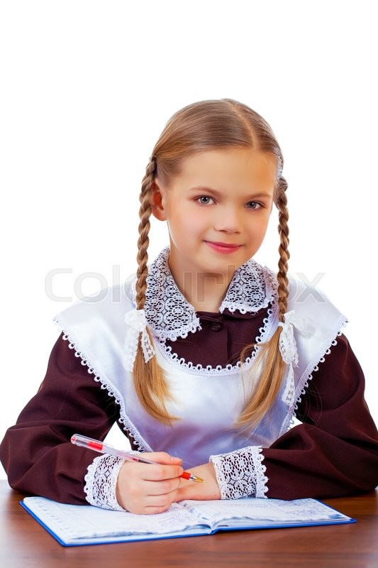 Young beautiful schoolgirl sitting at a desk, isolated on a white