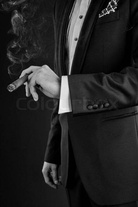 Man in a black suit holding a cigar in Stock image