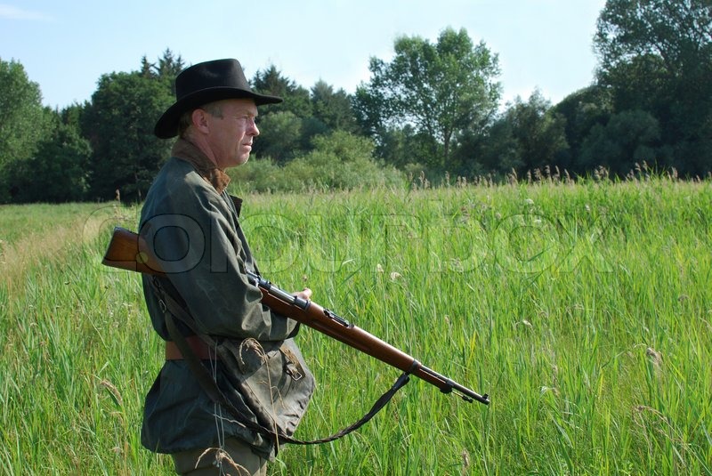 Jäger wartet mit seinem Gewehr Stockfoto Colourbox