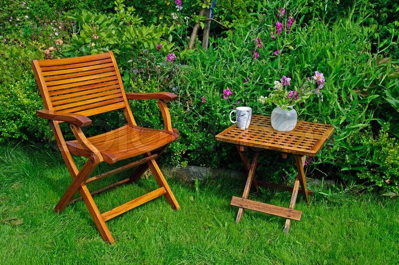 A hardwood garden chair and table, cup of coffe and a vase with flowers. | Stock Photo | Colourbox