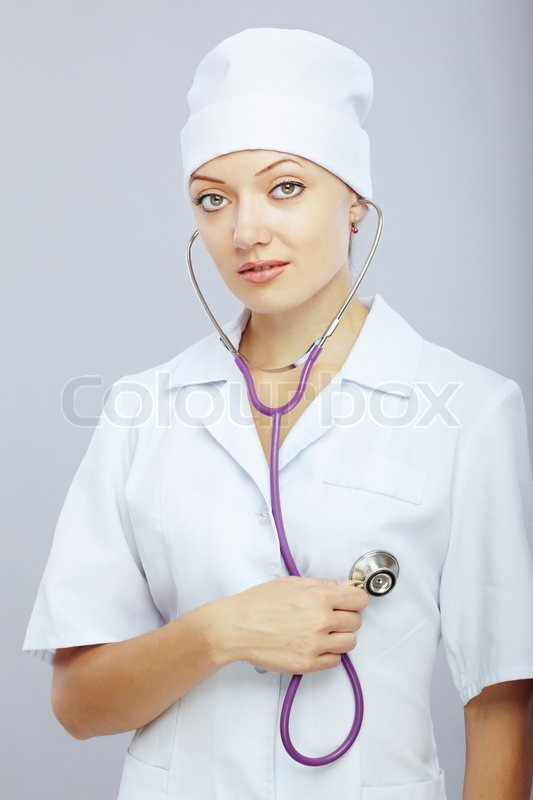 Young female doctor with stethoscope monitoring her heart | Stock Photo