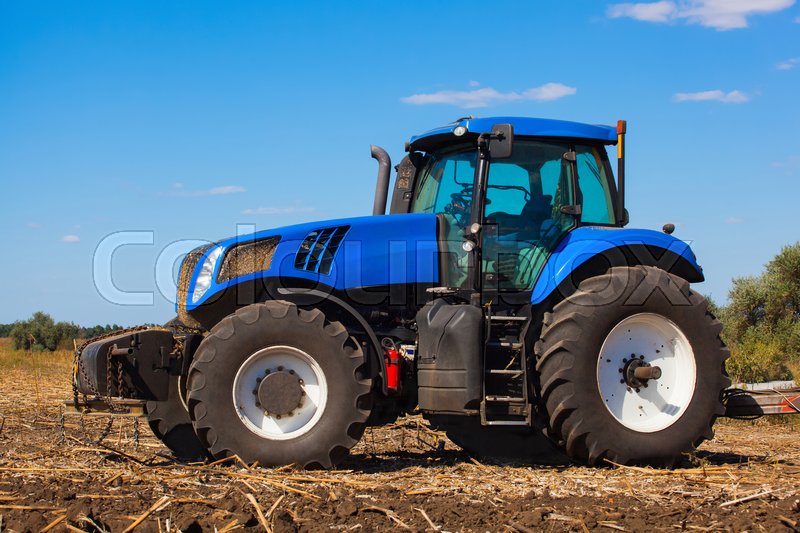 Big blue tractor plows the field and Stock image Colourbox