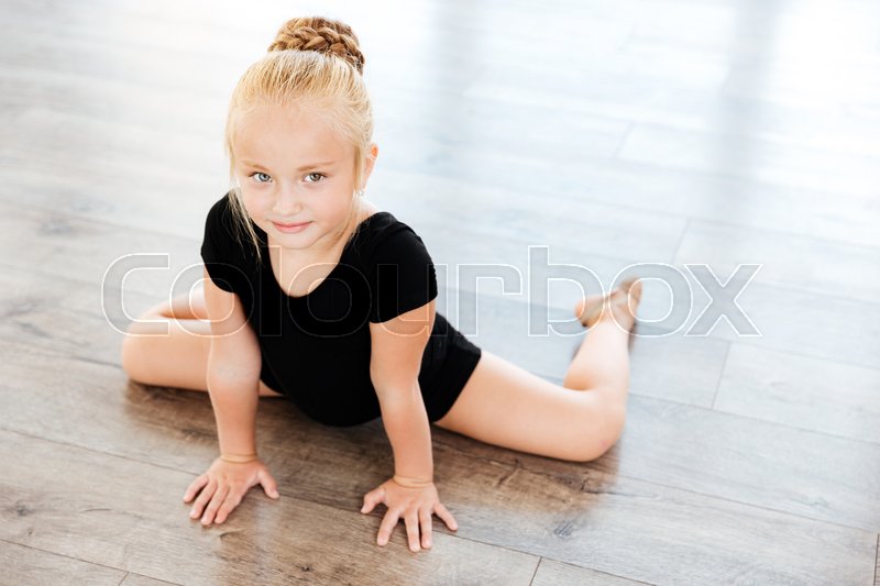 cute little girl ballerina stretching on the floor in dance studio
