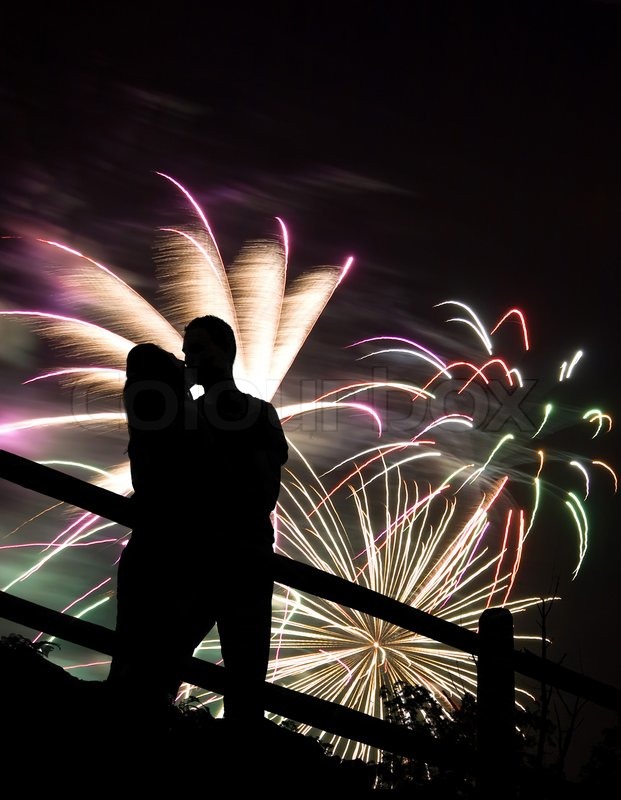 A silhouette of a kissing couple in front of a huge 
