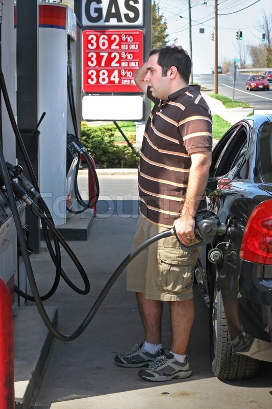 A man pumping high priced gas into his car with a disgusted look on his  face | Stock image | Colourbox