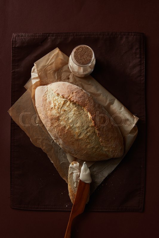 Fresh wheat bread on parchment, slice | Stock image | Colourbox
