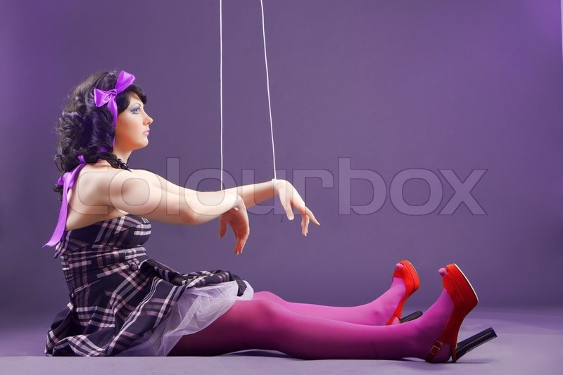 Fashion model stylized as doll sitting on violet studio