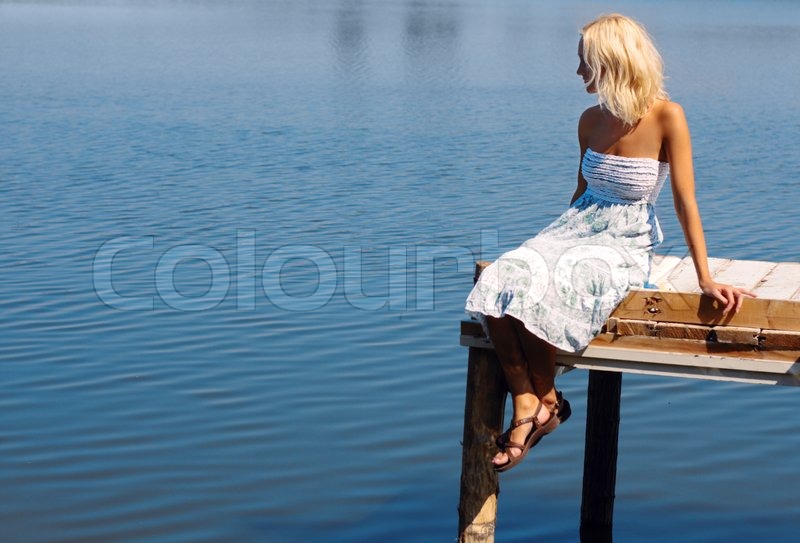 Mädchen sitzt auf einem Pier am Stock Bild Colourbox