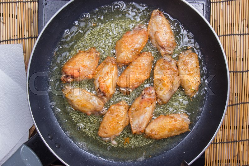 Chef frying chicken wings in pan / Stock Photo Colourbox