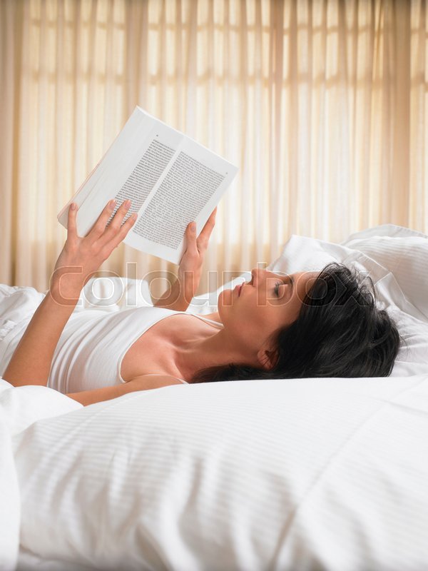 Woman reading a book in bed | Stock image | Colourbox