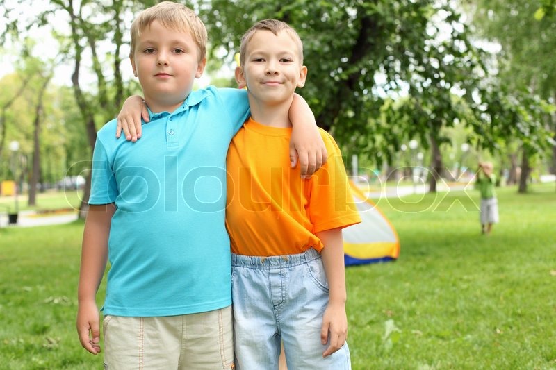 two boys standing next to each other in the summer park stock