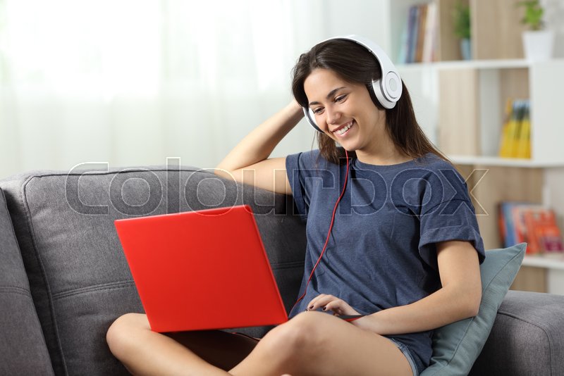 Happy Teen Watching Videos Online In A Red Laptop Sitting On A Couch In The Living Room At Home Stock Photo Colourbox Happy Teen Watching Videos Online In A Red Laptop Sitting On A Couch In The Living Room At Home Stock Photo Colourbox