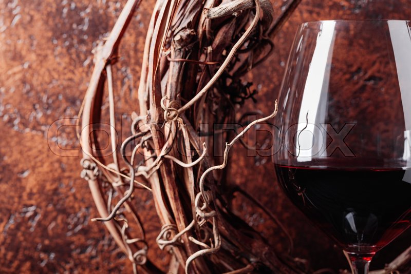 Dried vine and a glass of red wine. Stock image Colourbox