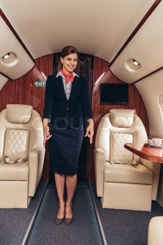 smiling flight attendant in uniform showing gestures in private plane |  Stock image | Colourbox