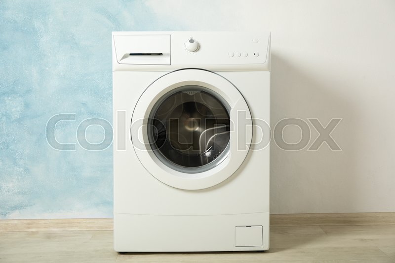 Modern washing machine against blue Stock image Colourbox