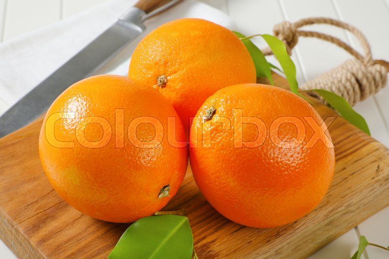 Three whole ripe oranges and leaves on Stock image Colourbox