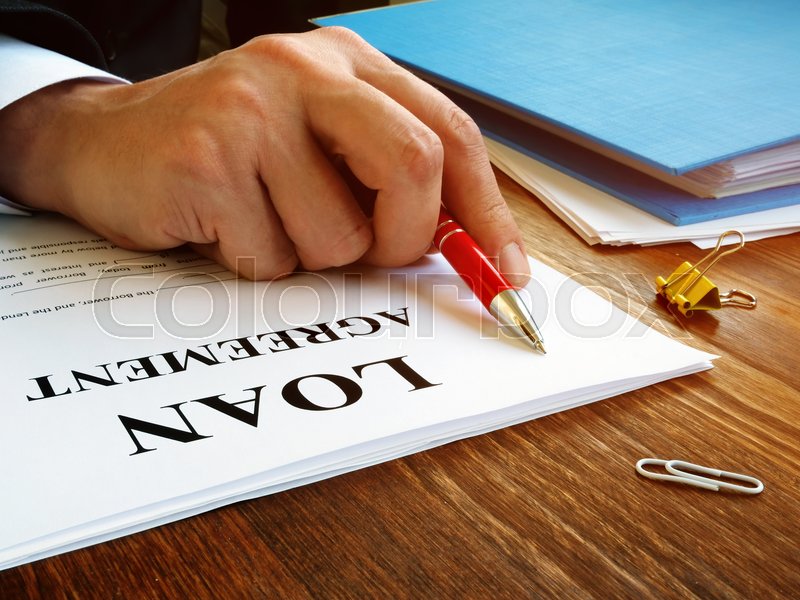Man reads loan agreement for signing. Stock image Colourbox