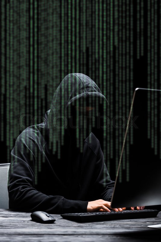 Hacker in mask sitting near computer ... | Stock image | Colourbox