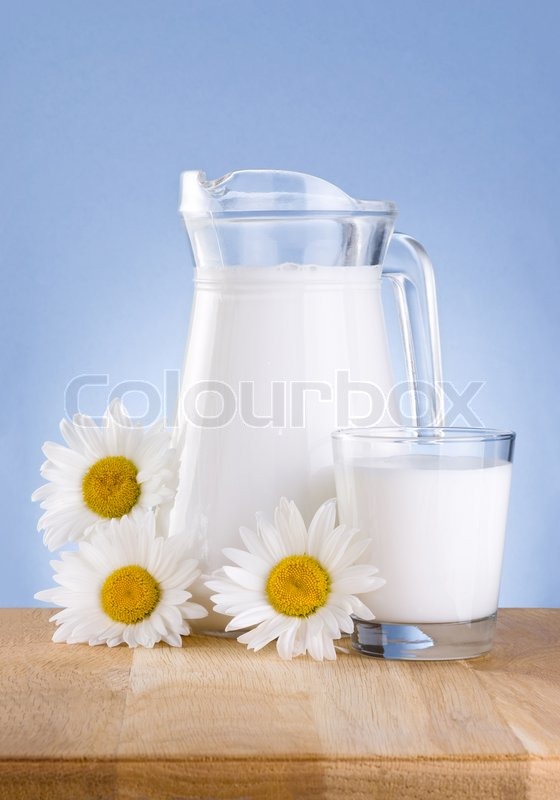 Jug frisk mælk , glas og tre kamille blomster er træbord pÃ¥ en blÃ¥ ... Blå træborde