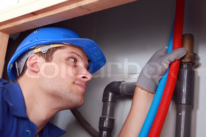 Plumber with hot and cold flexible water pipes | Stock image | Colourbox